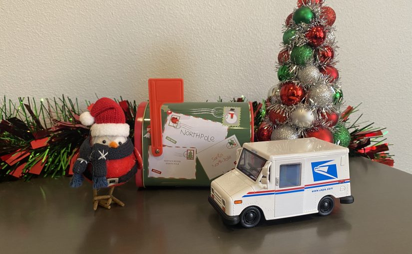 mailtruck for the usps in front of a holiday mailbox and christmas tree with a bird with a christmas hat