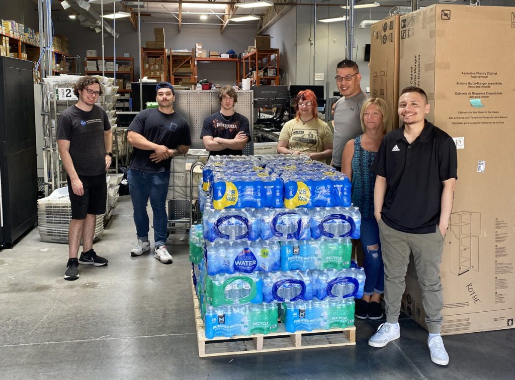 LetterStream staff standing in our printing and mailing facility next to donated water bottles